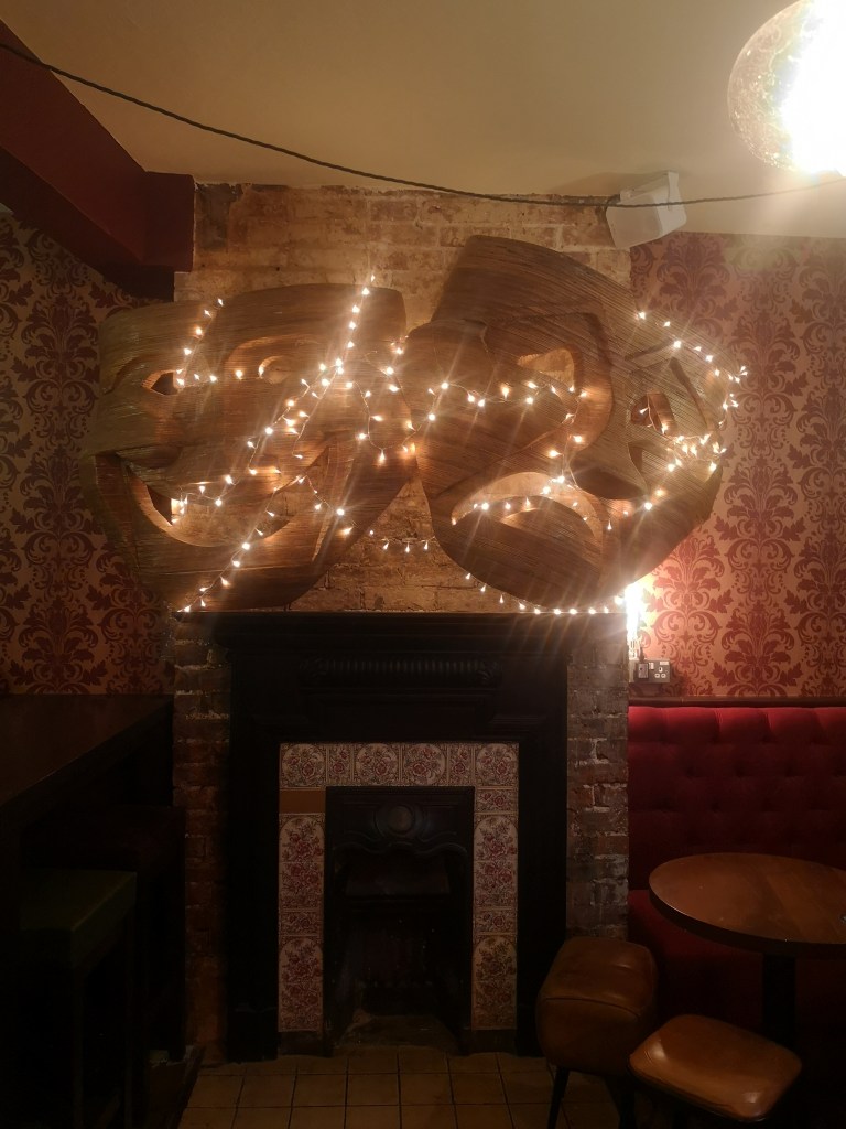 Theatre mask art with fairy lights at The Actors